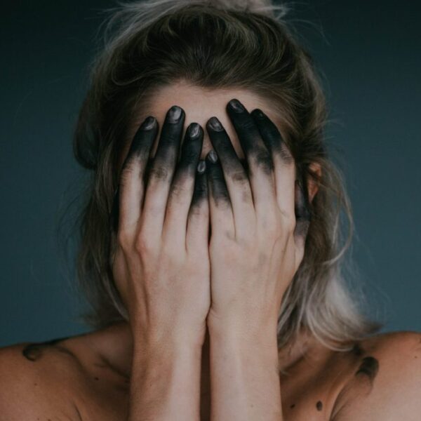 Kobieta zakrywa twarz pobrudzonymi rękami